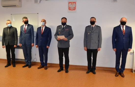 3. Komendant odczytuje list gratulacyjny, obok samorządowcy, nowy komendant komisariatu i emerytowany policjant.JPG